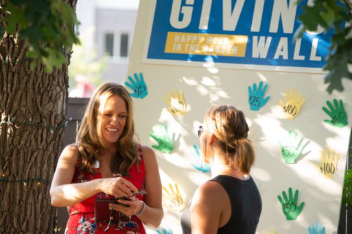 Burns stands before a Giving Wall marked with donations.