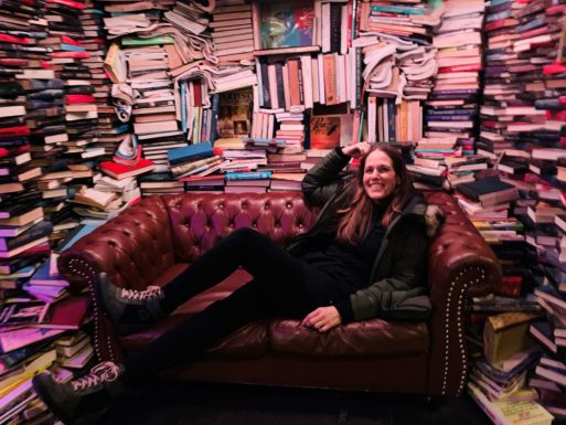 Burns, who supports bereaved children, lays on a couch surrounded by books.