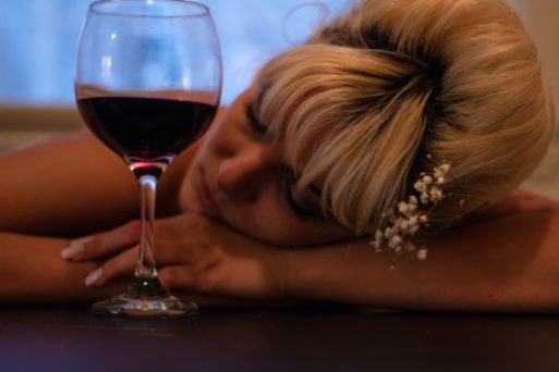 A woman sleeps next to a glass of red wine -- a potential victim of the rising death toll due to alcoholism.