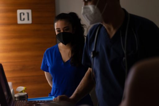 Two medical workers look at death toll statistics on the computer.