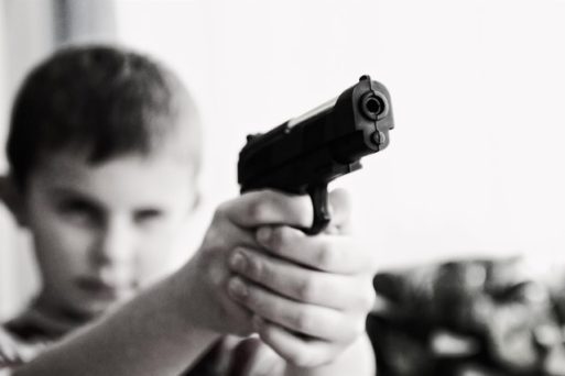 A child holds a gun, representative of their susceptibility to gun deaths.