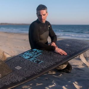 Dan Fischer reads the names in the One Last Wave Project on his surfboard.