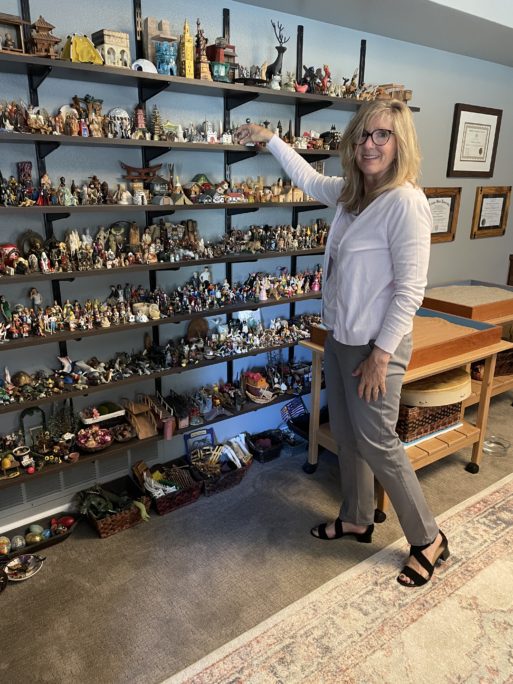 Shannon Yockey poses with a shelf full of sandplay figures.