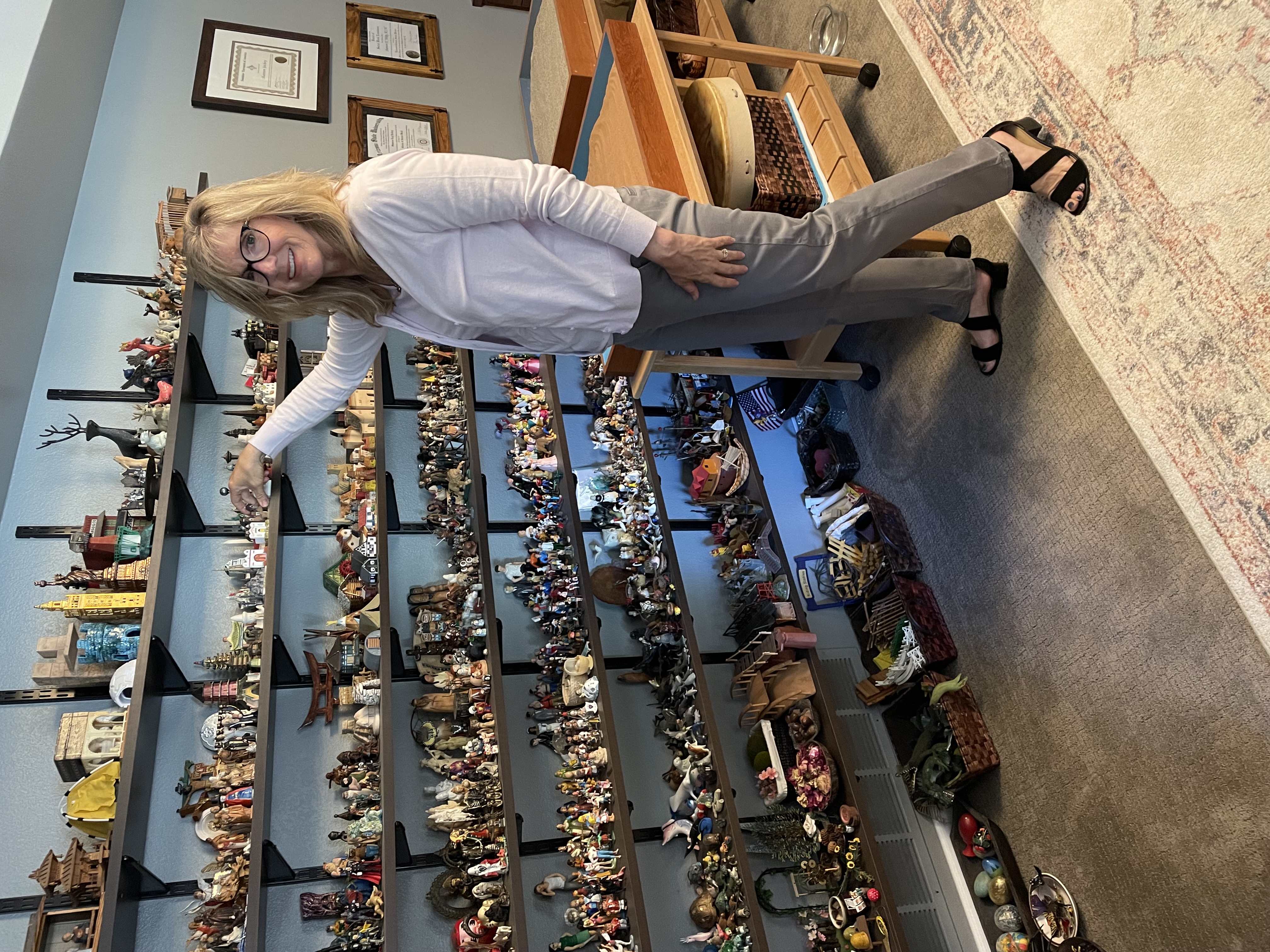 Shannon Yockey poses with a shelf full of sandplay figures.