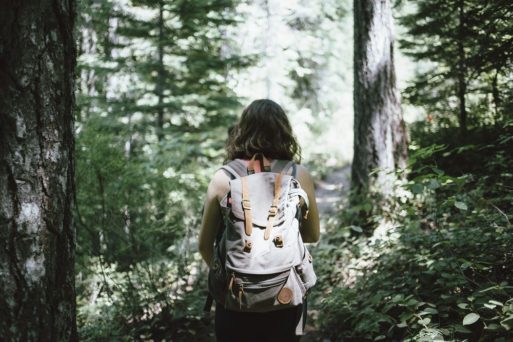 woman walking through forest with back pack and trail basket