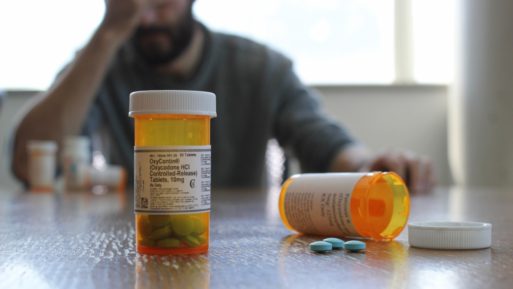 discouraged man looks at bottles of opioid tapering