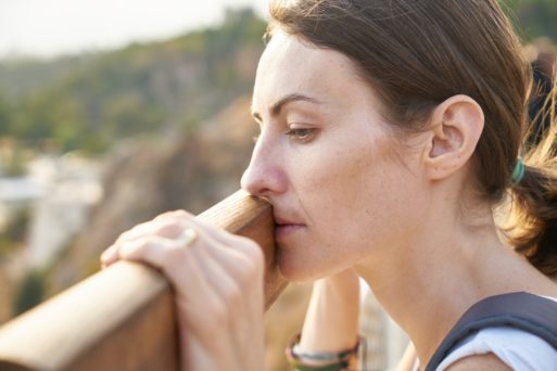 woman with depression looks over a railing