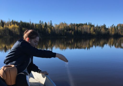 a woman scatters cremation ashes over water