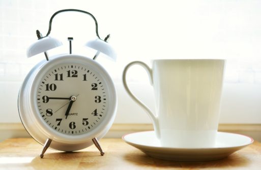 old fashion alarm clock near mug