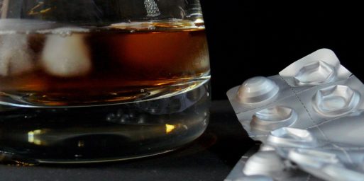 A cocktail glass and empty pill packet indicate alcohol abuse.