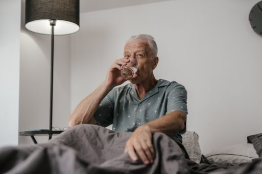 An elderly man drinks a glass of water, as new research links hydration with healthy aging.