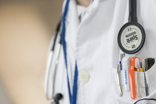 person wearing a white lab coat with pens in pocket and stethoscope shows doctors' emotions