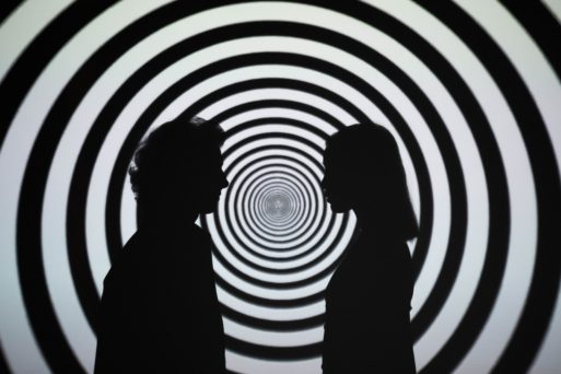 A couple in silhouette regards each other against a psychedelic background.