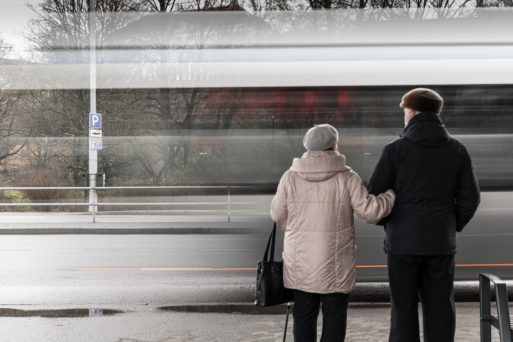 A senior couple waits at a fake bus stop.