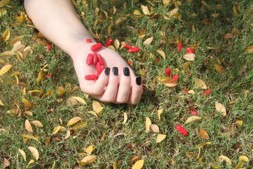 hand of a young woman holding pills in overdose death