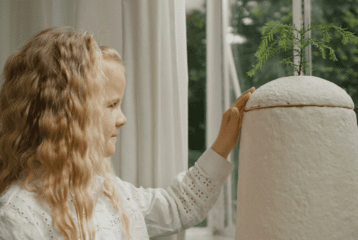 A young girl touches a mushroom urn