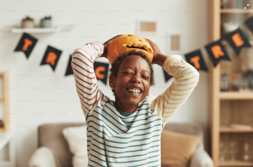 Girl with pumpkin on her head at halloween