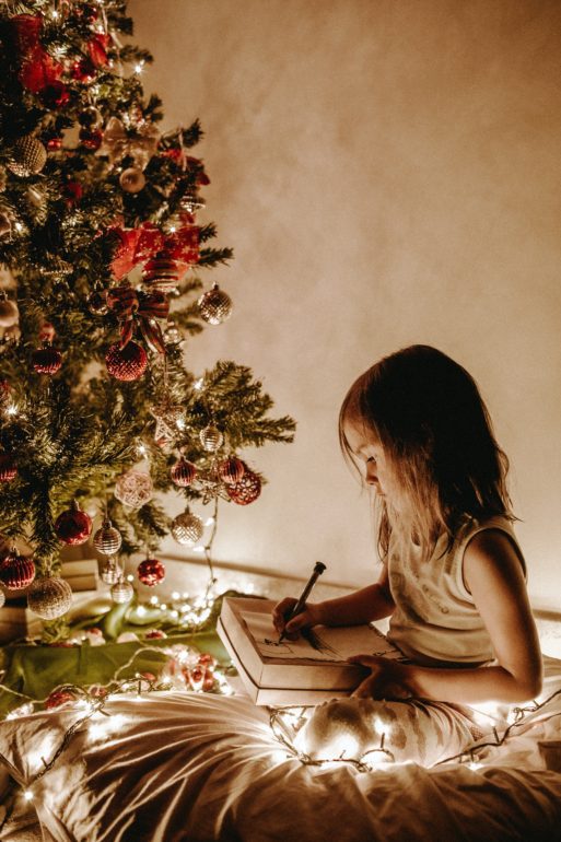 young girl drawing under a Christmas tree happy holidays