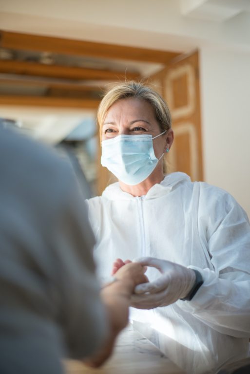 A nurse wearing a mask and gloves provides hospital-at-home care