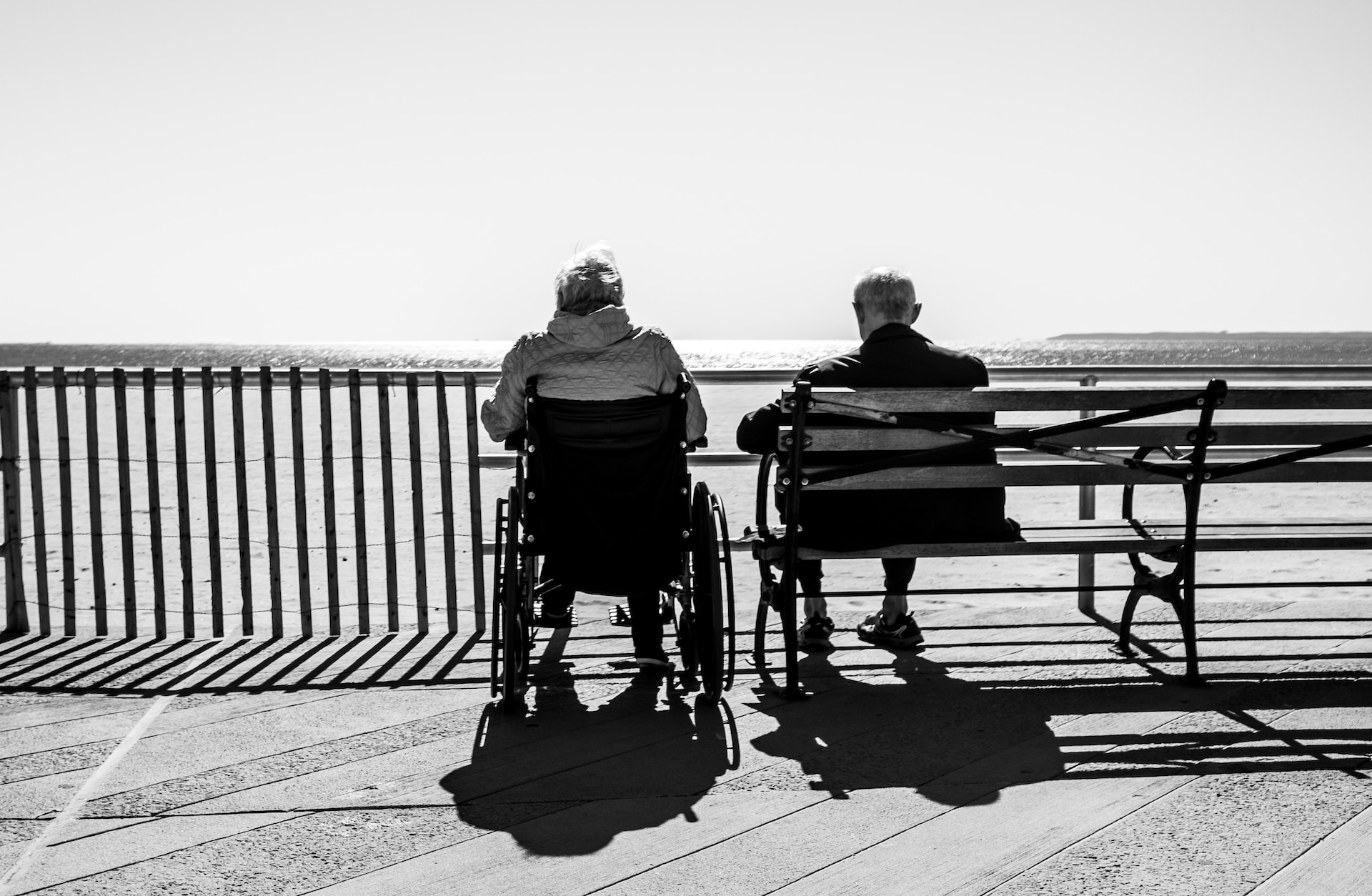 Two elderly men sit and look at the ocean, wondering if hospice misconceptions about length of life are true