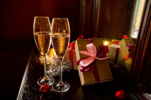 Two lonely glasses of champagne sit on a table with wrapped gifts, suggesting New Year's resolutions..
