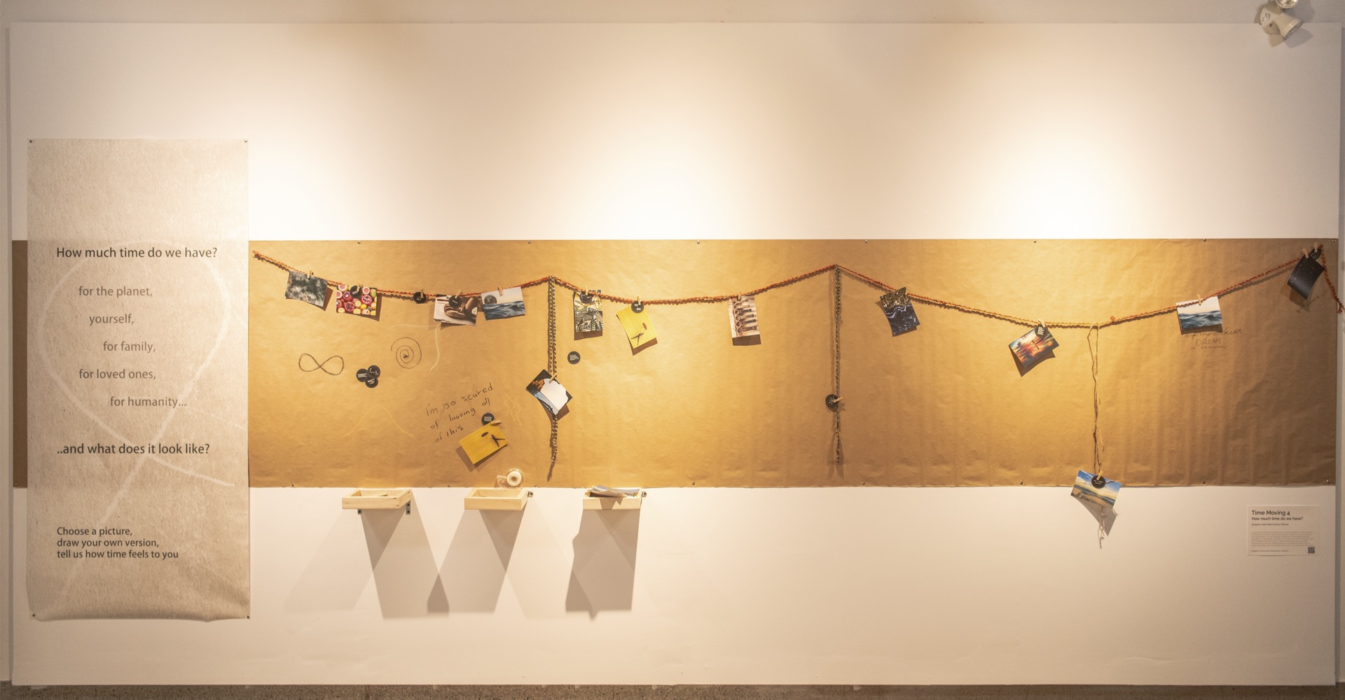 Extended horizontal work of art with pictures clipped to a cable.