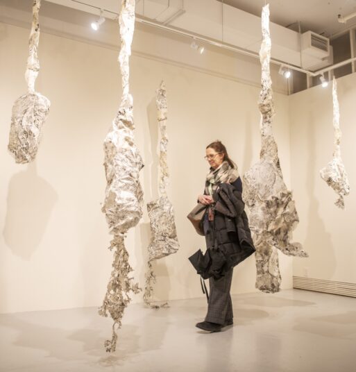 Woman walks through art display with amorphous shapes hanging from ceiling at Dying.exhibit 2023