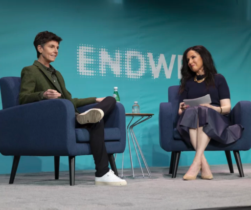 Two women are sitting in blue easy chairs on a stage with a modern side table between them. discussing how Hollywood gets death wrong