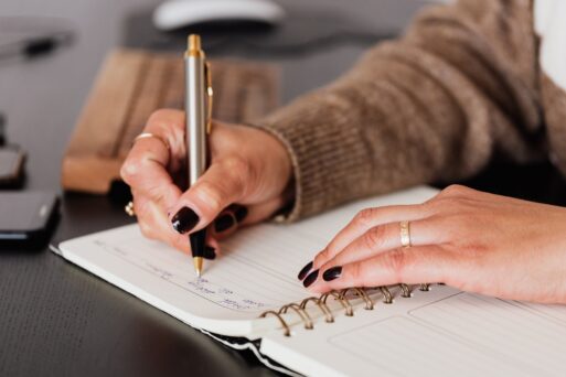 Close up of woman taking notes on a notebook after recording conversation with loved one