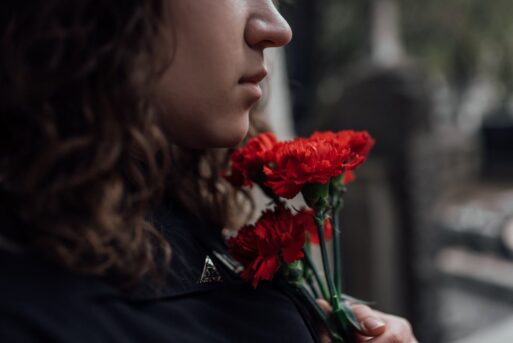 A woman experiencing grief holds a handful of carnations.