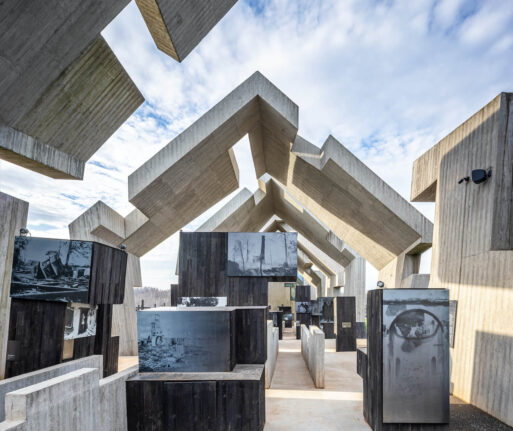 An open-air room built of blocky concrete houses museum displays of black and white images of the destruction wrought by the pacification of Polish people in Michniów