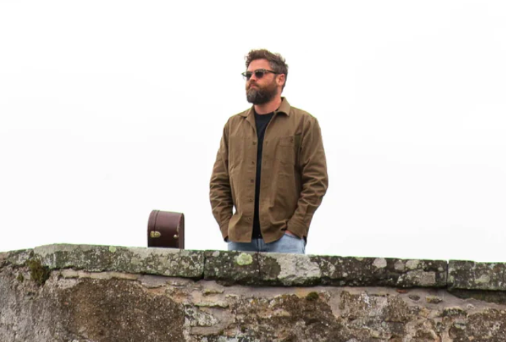Passenger, who sings "Life's for the Living," looks out over a stone wall.
