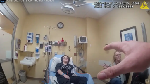 Still photo from body camera footage showing a person on a hospital bed, Nex Benedict, receiving treatment for their injuries after the assault