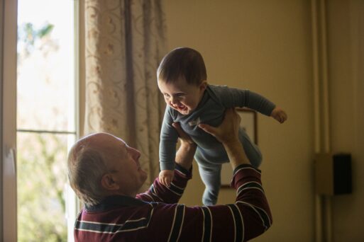 A grandfather joyfully tosses a baby into the air