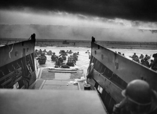 A black and white photo of soldiers storming Normandy on D-Day, from the perspective of one of the boats