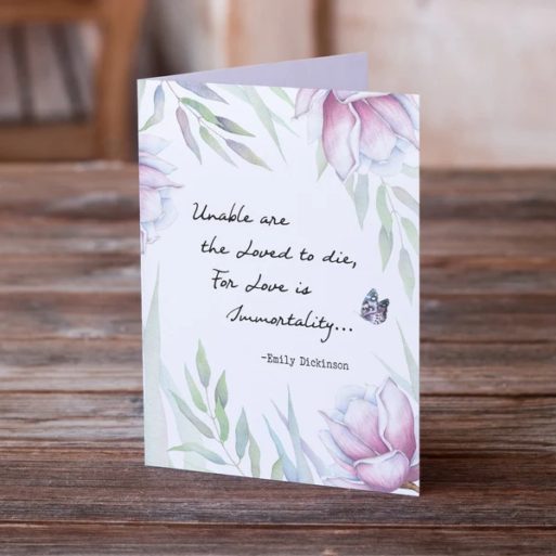 A card with a floral design has the Emily Dickenson quote, "Unable are the loved to die, for love is immortality"