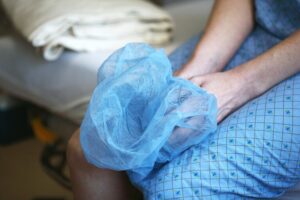 A person sits on a hospital bed holding a disposable cap