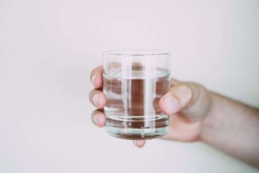 A hand extends a glass towards someone with dementia suffering from hot weather.