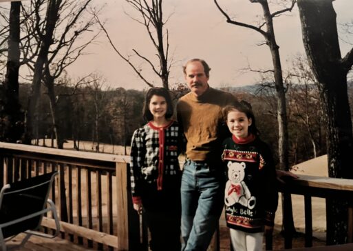 Cassandra and her sister standing with their father in the back yard.