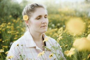 A woman with eyes closed in a field of flowers