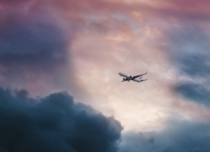 Far view of an airplane in a clouded yet bright sky