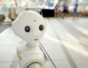 A cute robot looks at the camera with blurry people in background