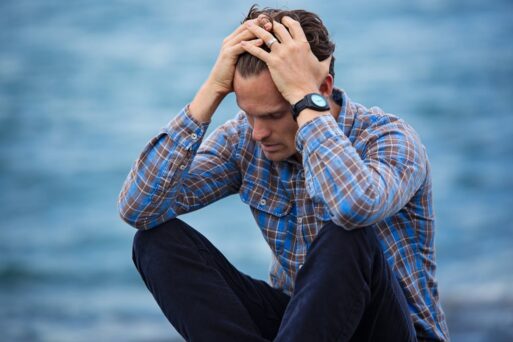 A man in a blue checkered shift holds his head in an expression of election grief.