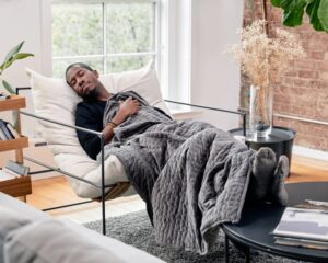 Man on a chair under a weighted blanket