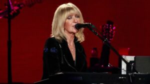 Christine McVie sings into a microphone at the piano