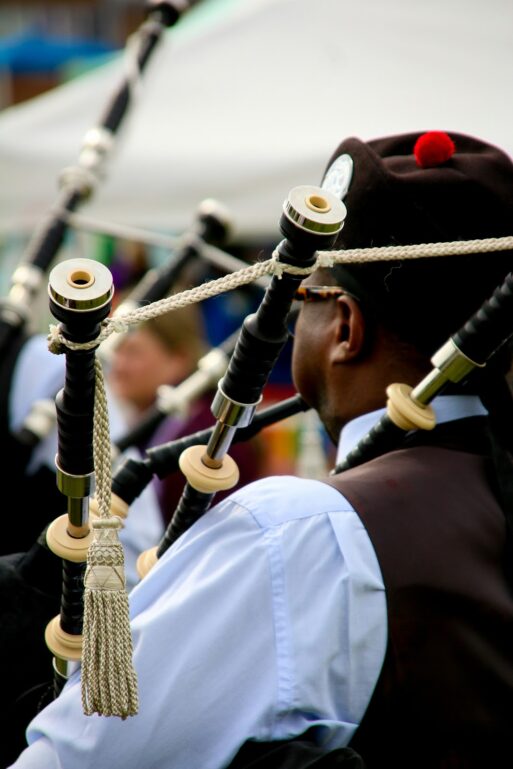 A man in traditional Celtic garb plays live music on the bagpipes.