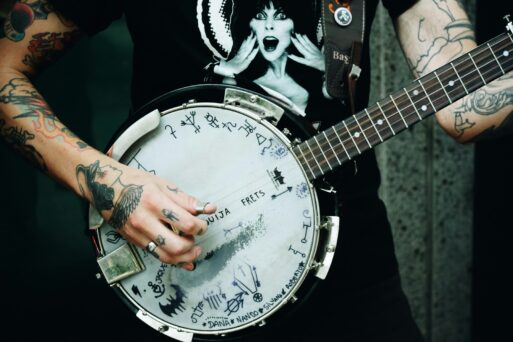 We can see a heavily-tattooed arm and hands of someone playing the banjo, which is likewise "tattooed" with graphics