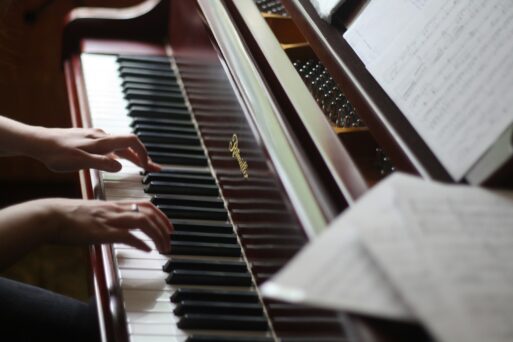 A woman's hands gracefully hover over the keys of a piano that has been polished to a sheen