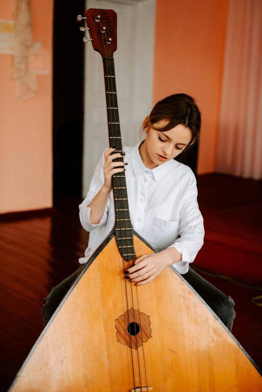 A young woman plays live music on a very large stringed instrument called the Russian Balalaika