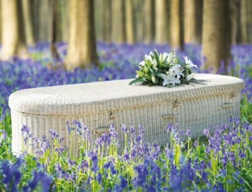 A wicker coffin with a bouquet on top sitting in a field of bluebonnets.